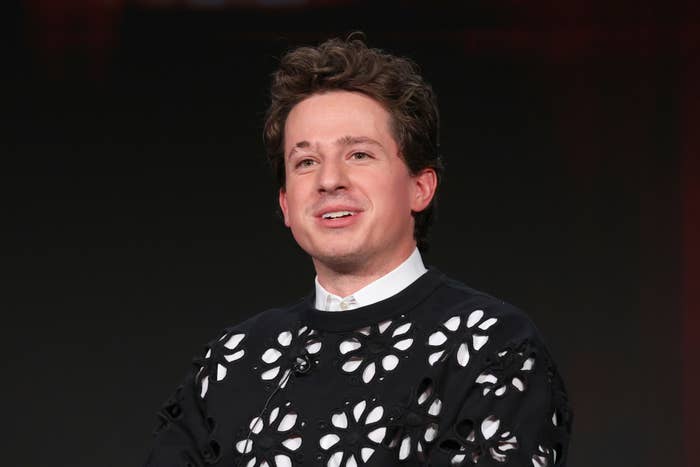 Charlie Puth wearing a dark sweater with floral cutouts and a shirt