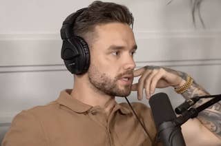 Liam Payne with short dark hair and a beard wearing headphones and a brown polo shirt, speaking into a microphone, appears to be in a podcast setting